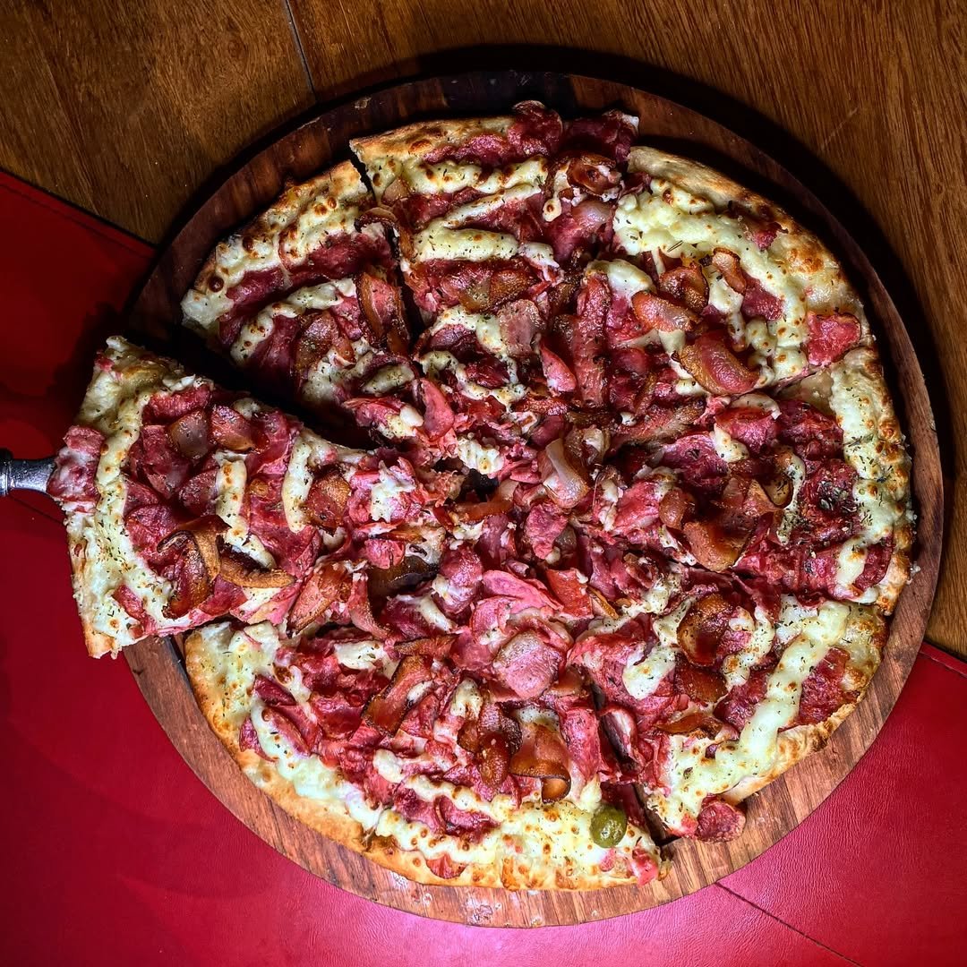 Pizza de carnes sendo servida